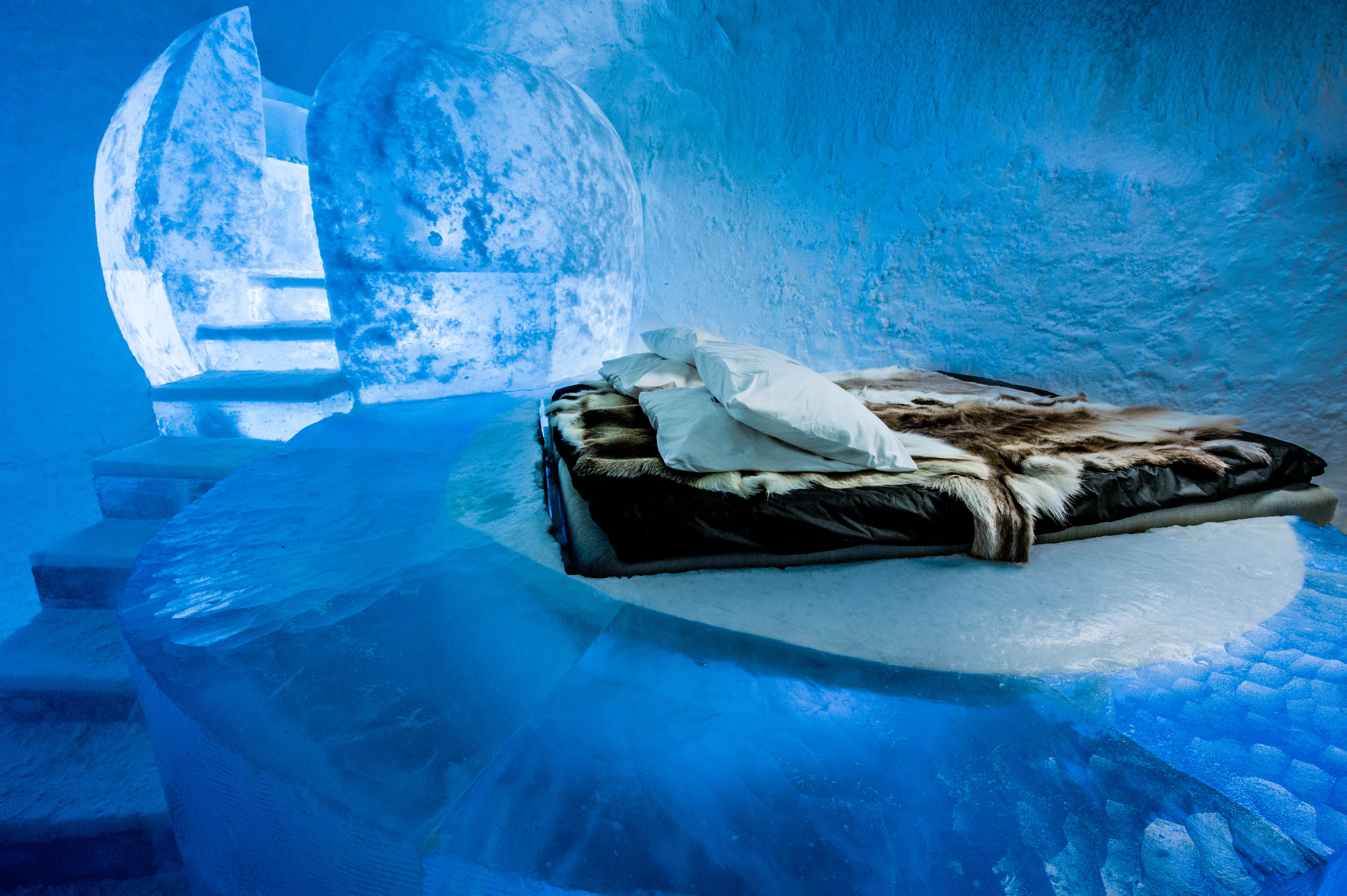 A carved ice hall lit in cold blue with a bench of snow along one wall