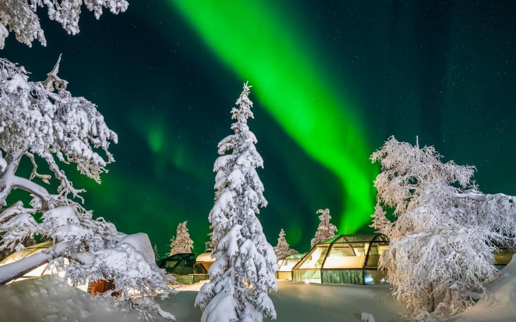 Glass-roofed cabins spaced along a snow-covered slope at dusk